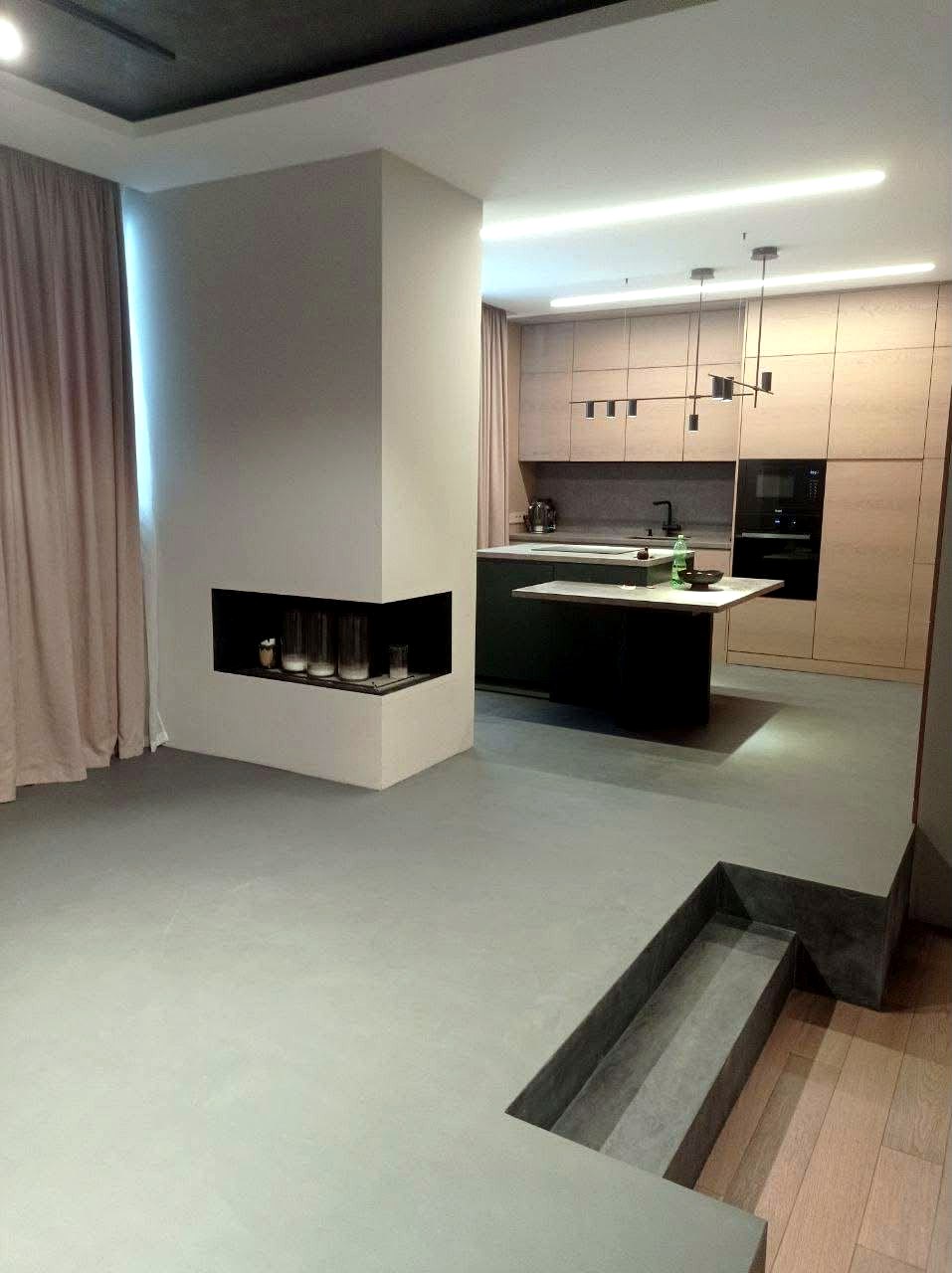 Open-plan kitchen and living room floor finished in warm grey microcement with fireplace, Lancashire home renovation